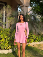 Woman in a pink dress standing outdoors with greenery around
